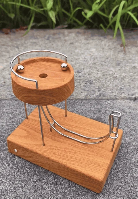 A steel ball circles the wooden bowl, drops onto the curved track and rises back into the bowl.