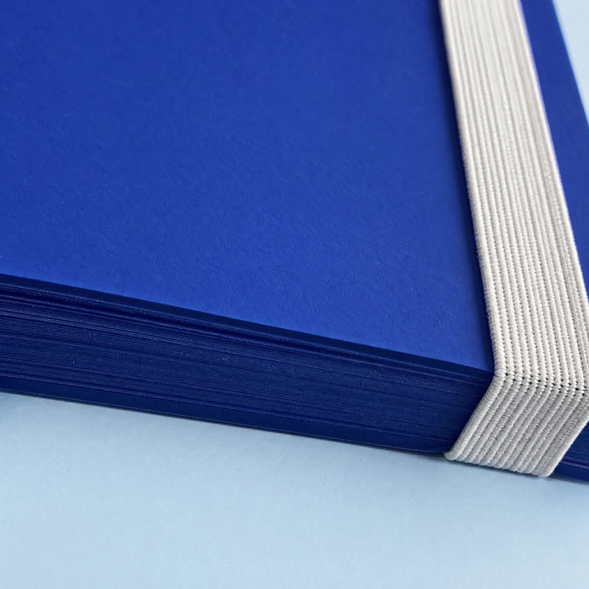Close view of the blue paper edges, rounded cover and white elastic strap
