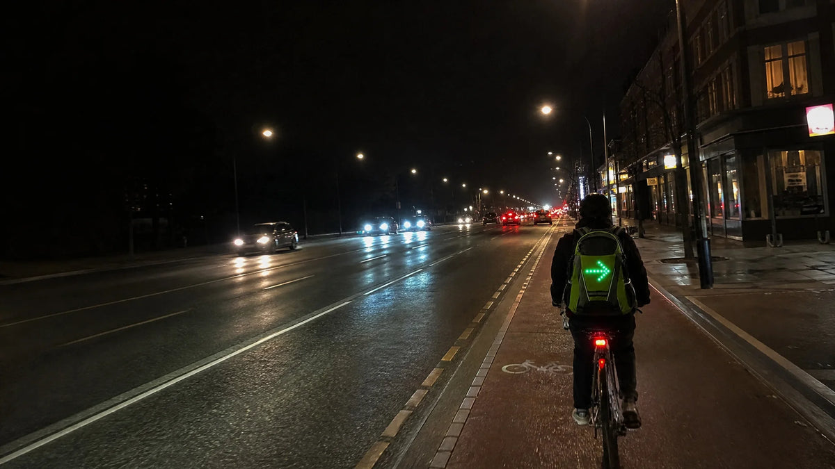 Cyclist signalling right on a city avenue after dark