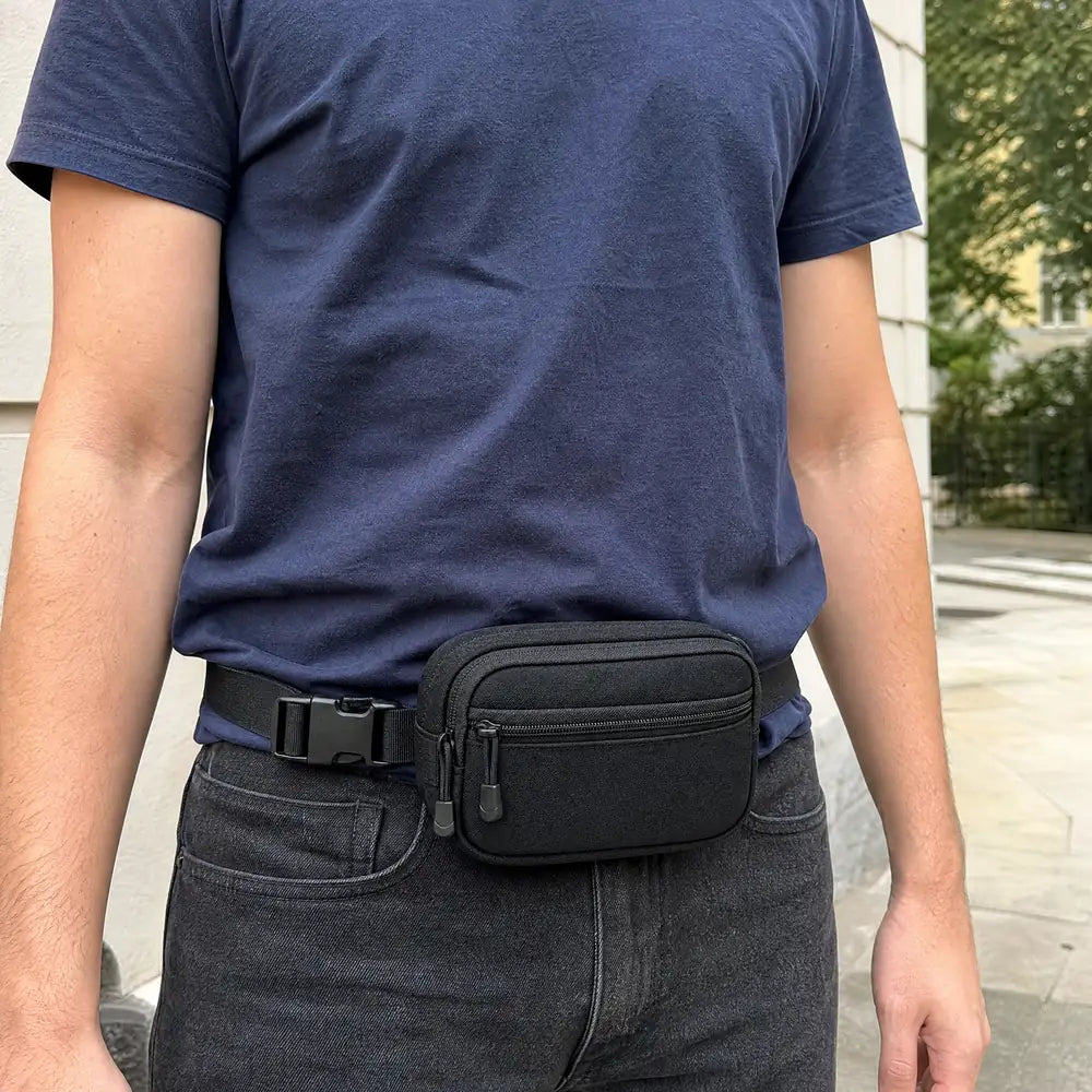 Adult wearing the closed black CloseCarry pouch at the waist outdoors.