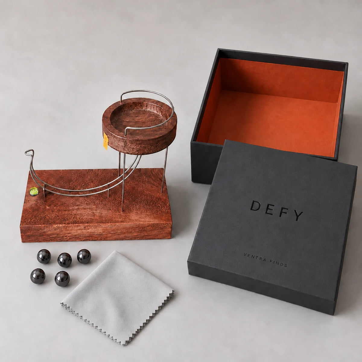 DEFY kinetic sculpture, branded presentation box, care cloth and five complimentary metal balls