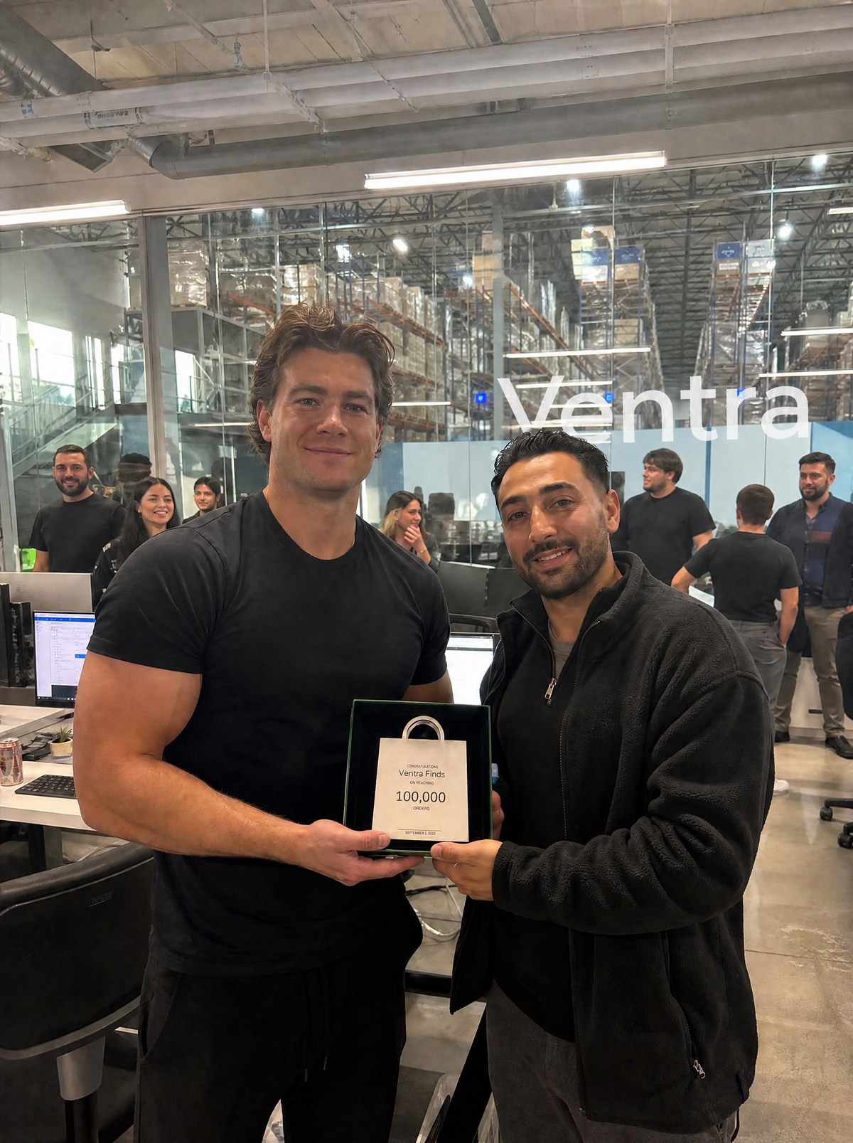 Two people holding the Ventra Finds 100,000-order Shopify milestone plaque.