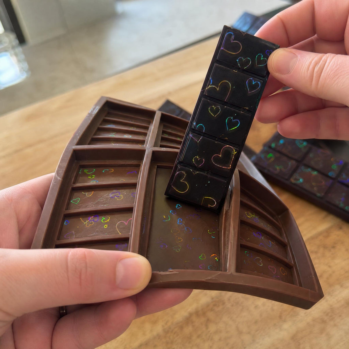 Bending the flexible silicone mold to pop out a holographic heart chocolate bar