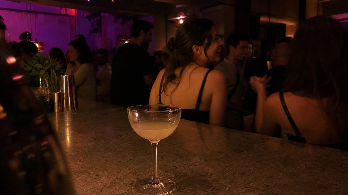 A drink left alone on a crowded bar counter