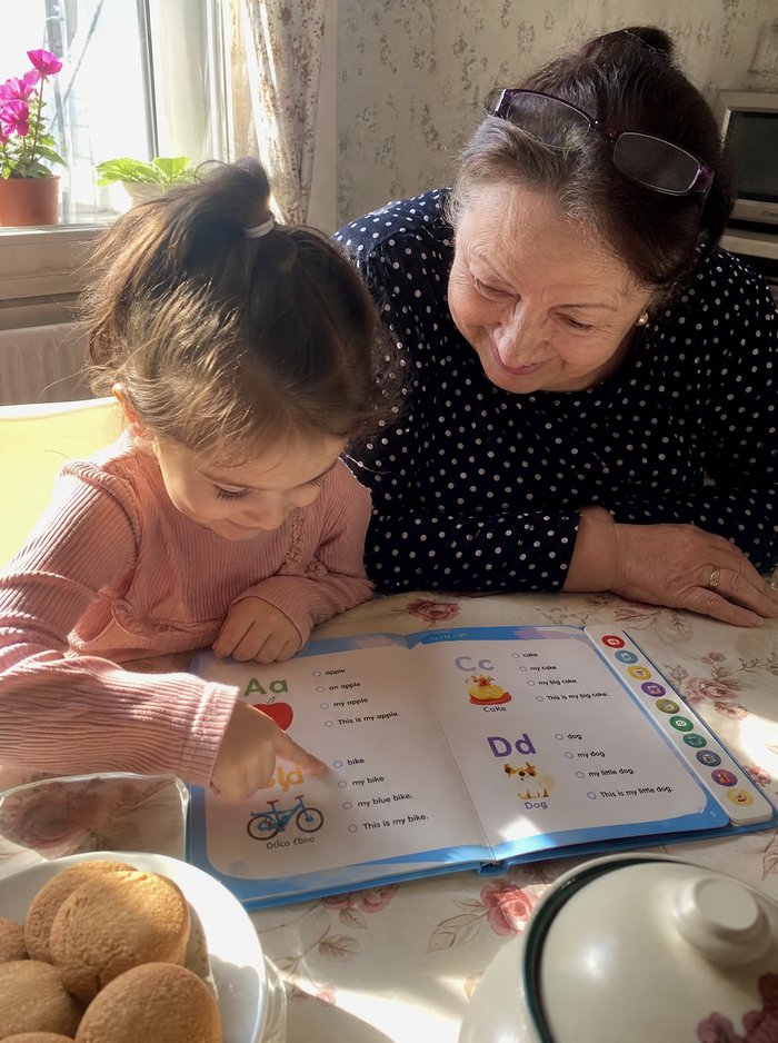 A grandmother and granddaughter reading at the kitchen table