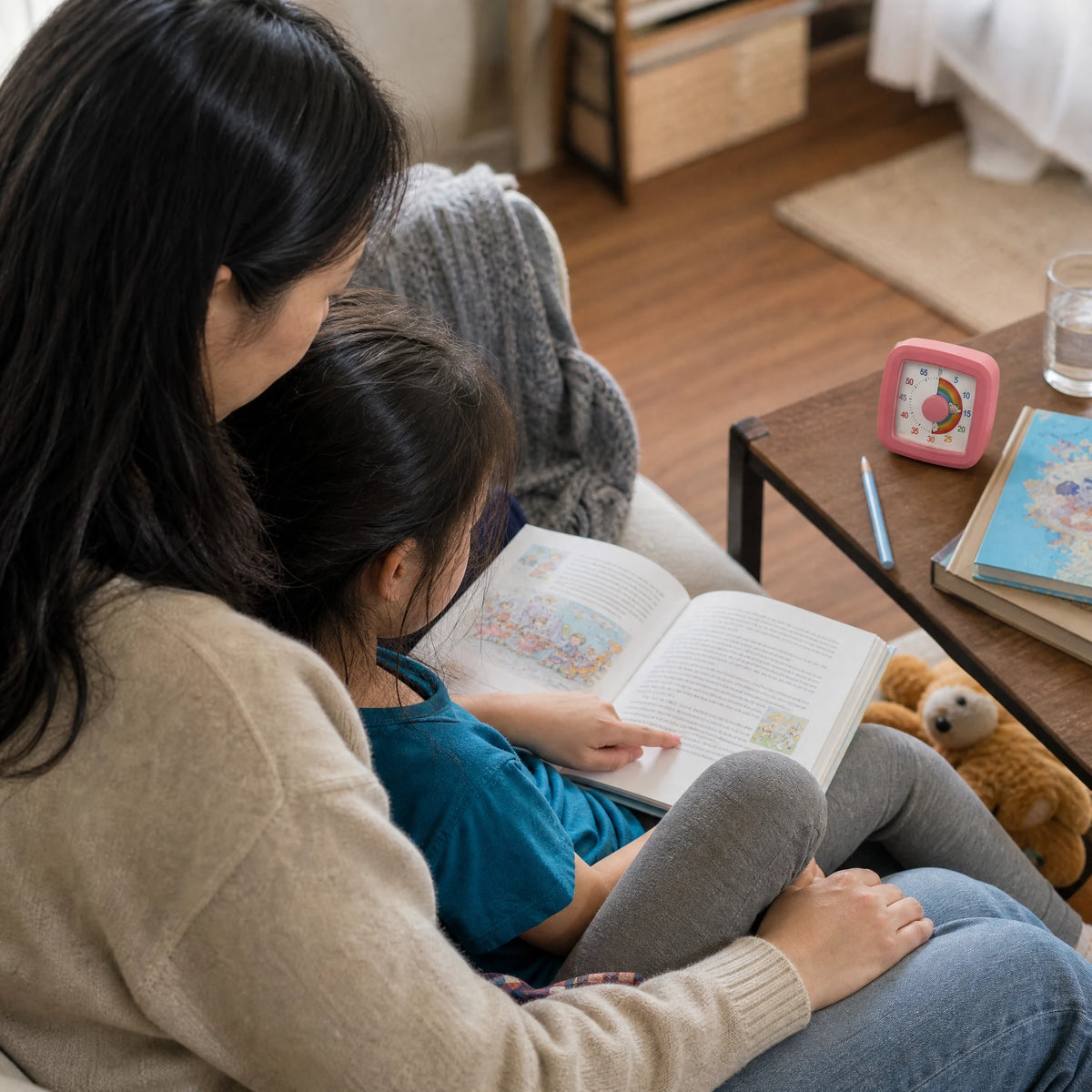 A parent and child share reading time with their visual timer nearby