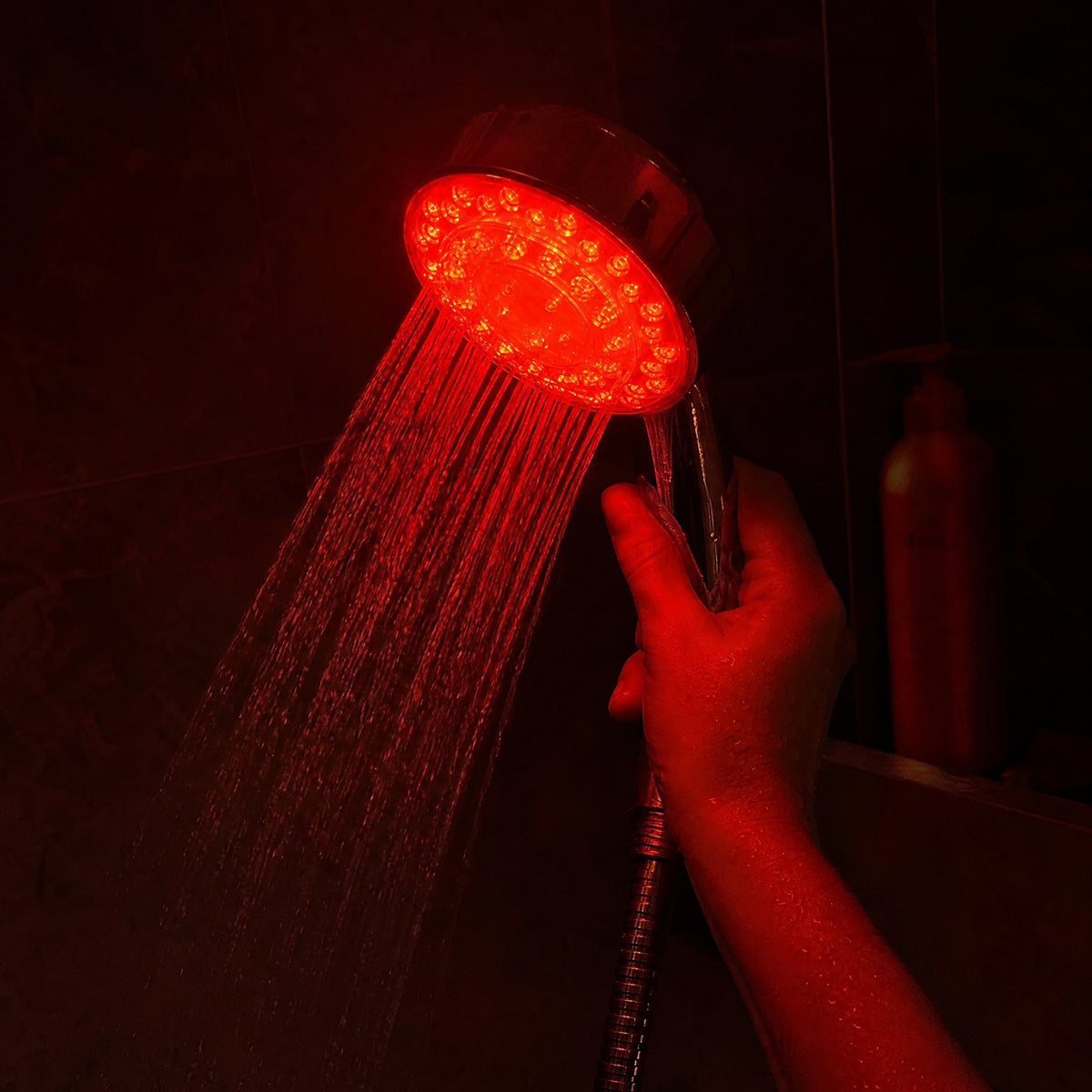 Handheld RUBRA glowing red in a dark shower