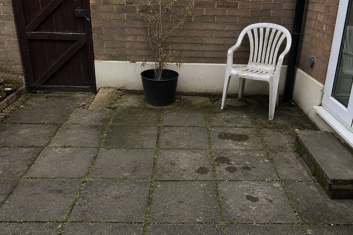 Grimy patio slabs with moss in the joints before cleaning