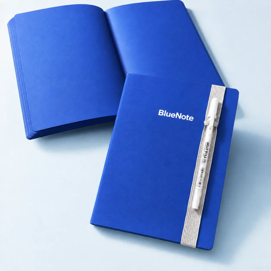 Two views of the BlueNote notebook: closed with pen and open to blue pages. One notebook included.
