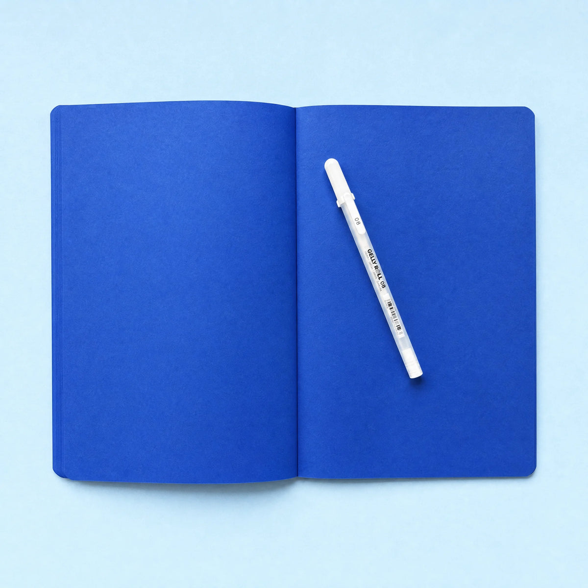 Open blank cobalt blue notebook with white gel pen