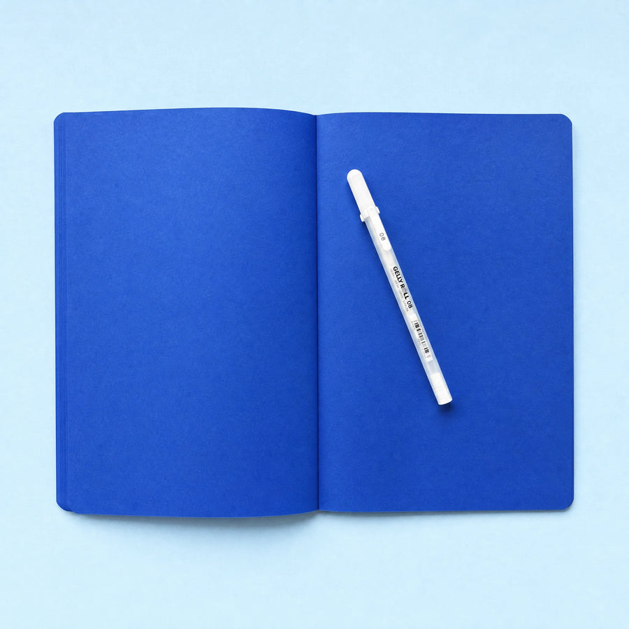 Open blank cobalt blue notebook with white gel pen
